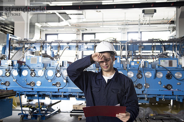 Techniker mit Klemmbrett in einer Fabrikhalle