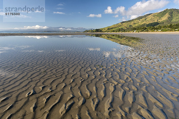 Neuseeland  Tasman  Golden Bay  Pakawau  Spiegelungen von Wolken im Wasser und Strukturen im Sand bei Ebbe
