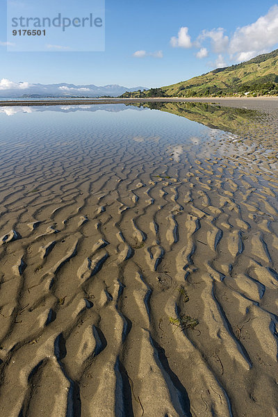 Neuseeland  Tasman  Golden Bay  Pakawau  Spiegelungen von Wolken im Wasser und Strukturen im Sand bei Ebbe