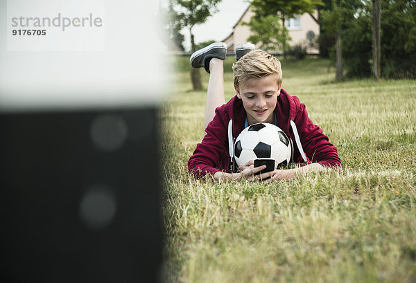 Deutschland  Mannheim  Teenager mit Fußball  mit Smartphone