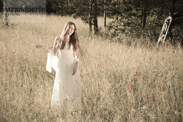 Porträt eines Mädchens im weißen Kleid auf der Wiese bei Gegenlicht