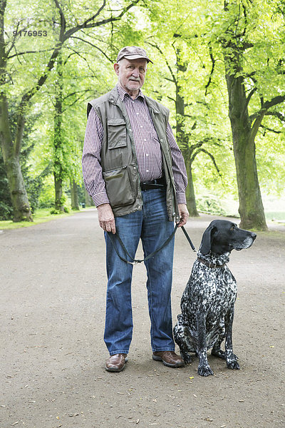 Senior mit seinem Deutsch Kurzhaarigen Zeiger im Stadtpark