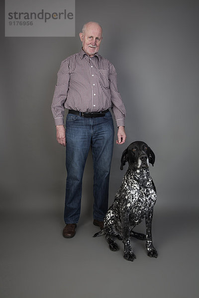 Senior Mann mit seinem Deutsch Kurzhaarigen Zeiger vor grauem Hintergrund