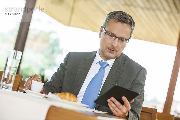 Geschäftsmann im Restaurant mit digitalem Tablett