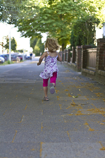 Kleines Mädchen rennt auf dem Gehweg