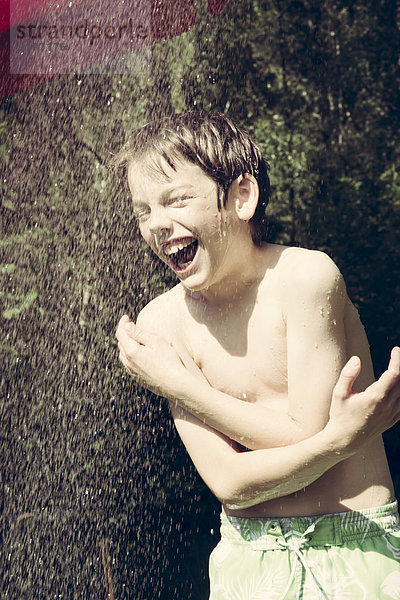 Porträt eines Jungen beim Duschen im Garten