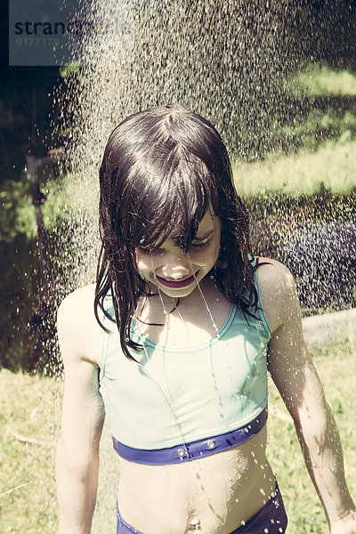 Kleines Mädchen beim Duschen im Garten