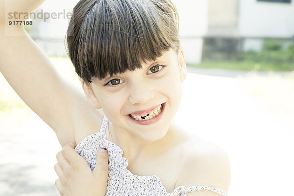 Porträt eines lächelnden kleinen Mädchens mit Zahnlücke  das ein Gesicht macht.