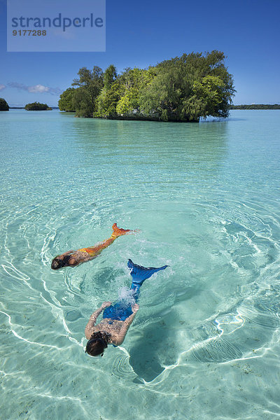 Palau  zwei junge Frauen in Meerjungfrau-Kostüm schwimmend in einer Lagune