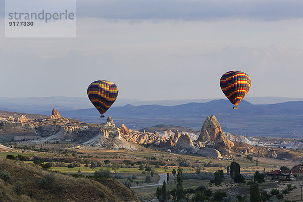 Türkei  Ostanatolien  Kappadokien  zwei Heißluftballons  die über Tuffsteinformationen im Goereme Nationalpark saugen.