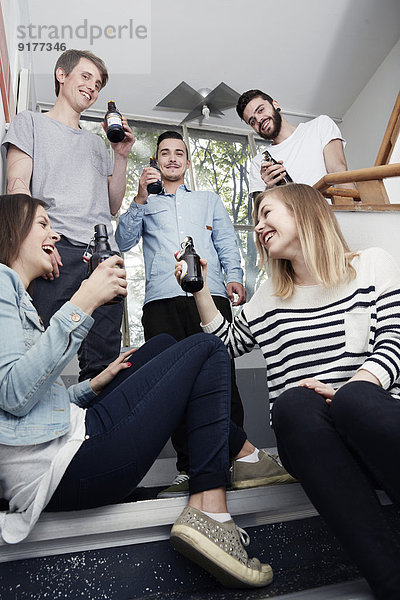 Gruppe von Kreativen  die im Treppenhaus Bier trinken