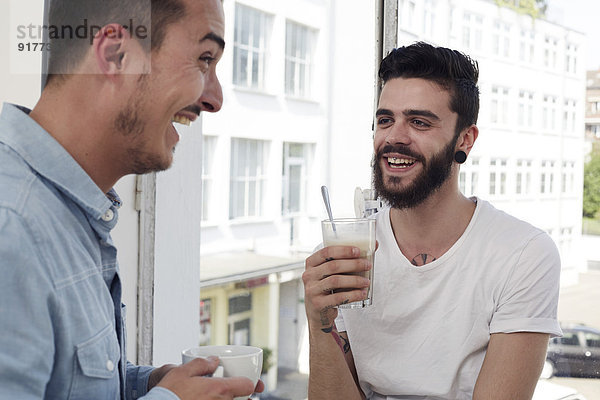 Zwei lachende Männer bei einer Kaffeepause im Büro
