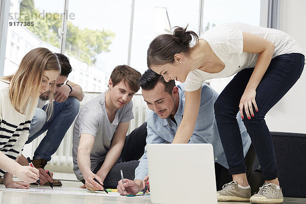 Gruppe von Kreativen  die auf dem Boden arbeiten