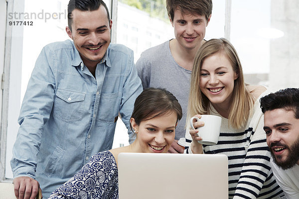 Gruppe von Kreativprofis mit Laptop am Tisch