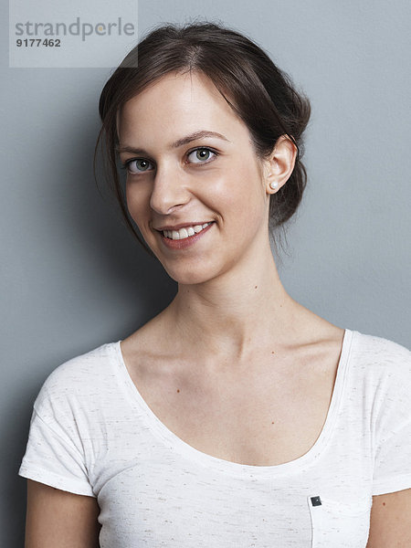 Porträt einer lächelnden brünetten Frau vor grauem Hintergrund