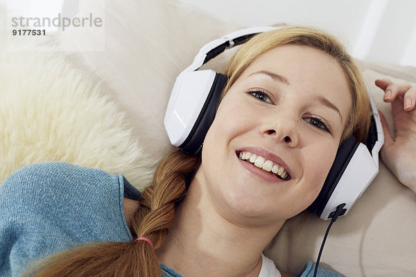 Porträt einer Teenagerin beim Musikhören mit Kopfhörern zu Hause