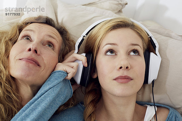 Portrait von Mutter und Tochter beim Musikhören mit Kopfhörern zu Hause