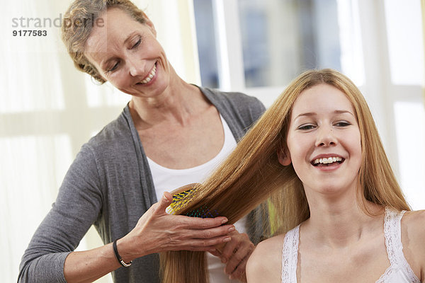 Mutter bürstet die Haare ihrer Tochter zu Hause