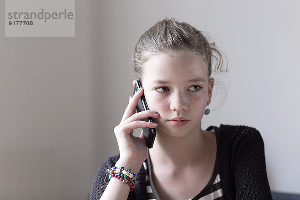 Portrait eines Mädchens beim Telefonieren mit dem Smartphone zu Hause