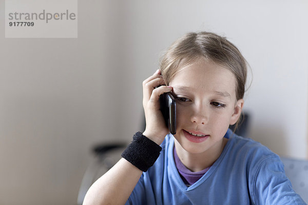 Portrait des Jungen beim Telefonieren mit dem Smartphone zu Hause