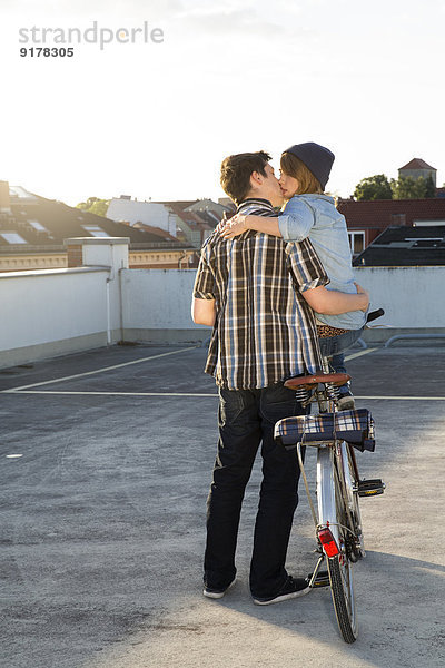 Teenager-Paar mit Fahrradküssen im Freien