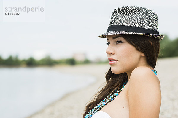 Porträt einer jungen Frau mit Hut am Strand