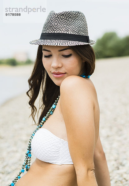 Portrait einer jungen Frau mit Hut am Strand