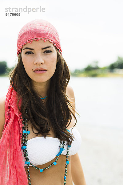 Porträt einer jungen Frau mit Kopftuch am Strand