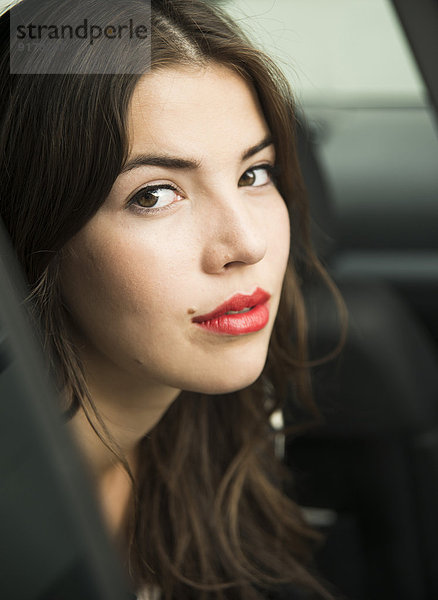 Porträt einer jungen Frau mit roten Lippen im Auto sitzend
