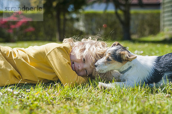 Junge spielt mit Jack Russel Terrier Welpe im Garten
