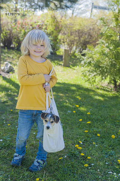 Junge mit Jack Russel Terrier Welpe in der Tasche