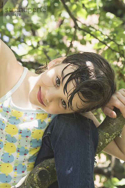 Porträt eines lächelnden kleinen Mädchens  das auf einen Baum klettert.