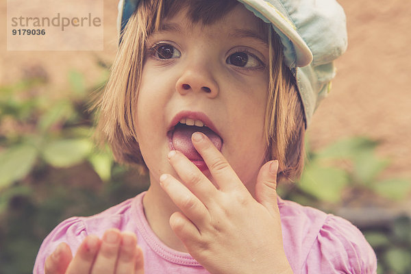 Porträt eines kleinen Mädchens  das rote Johannisbeeren isst.