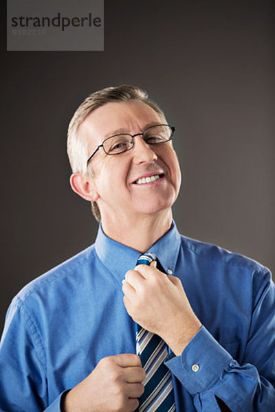 Porträt eines Geschäftsmannes  der seine Krawatte anpasst