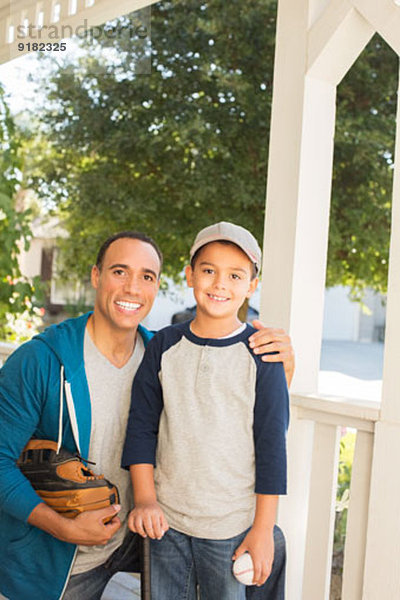 Porträt von Vater und Sohn mit Baseball und Handschuh auf der Veranda