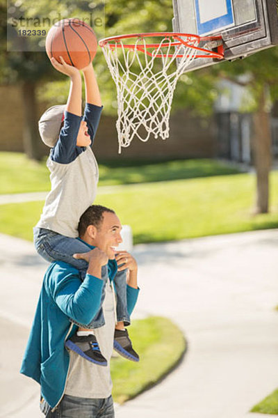 Vater und Sohn spielen Basketball in der Einfahrt