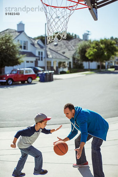 Vater und Sohn spielen Basketball in der Einfahrt