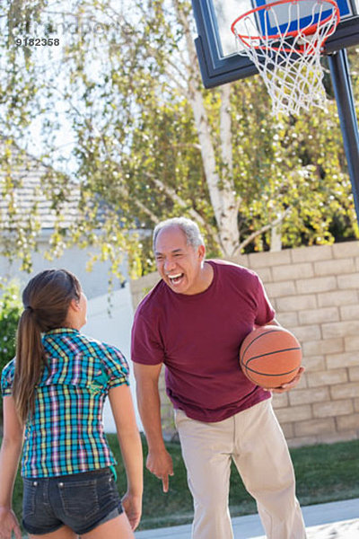 Großvater und Enkelin beim Basketball in der Einfahrt