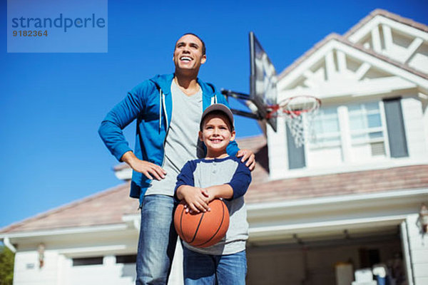 Vater und Sohn mit Basketball in der Einfahrt