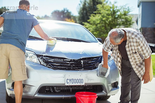 Vater und Sohn waschen Auto in der Einfahrt