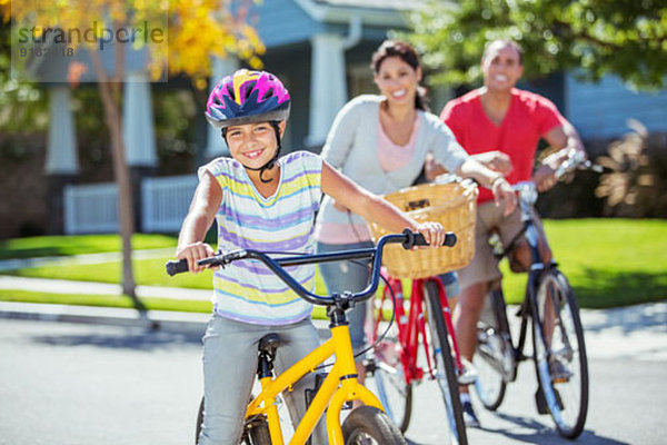 Porträt der lächelnden Familie beim Radfahren auf der Straße