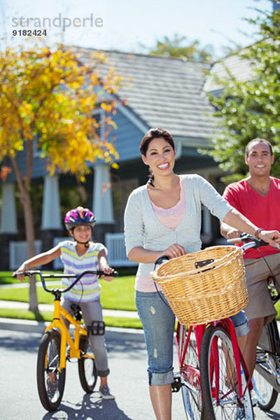 Porträt einer glücklichen Familie mit Fahrrädern in der Straße