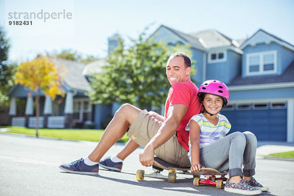 Vater und Tochter auf dem Skateboard sitzend