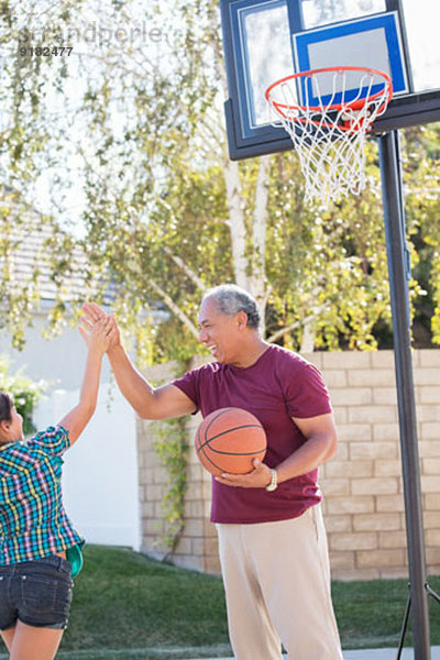 Großvater und Enkelin beim Basketballkorb hoch fünfzig