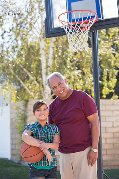 Portrait von Großvater und Enkelin beim Basketballspielen