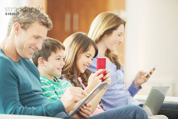 Familie mit Technik auf dem Sofa