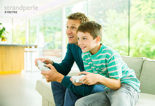 Vater und Sohn spielen Videospiele im Wohnzimmer