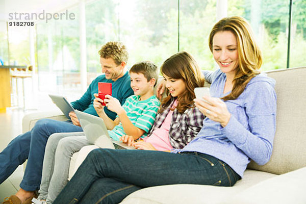 Familie mit Technik auf dem Sofa