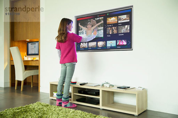 Mädchen mit Touchscreen-Fernseher im Wohnzimmer