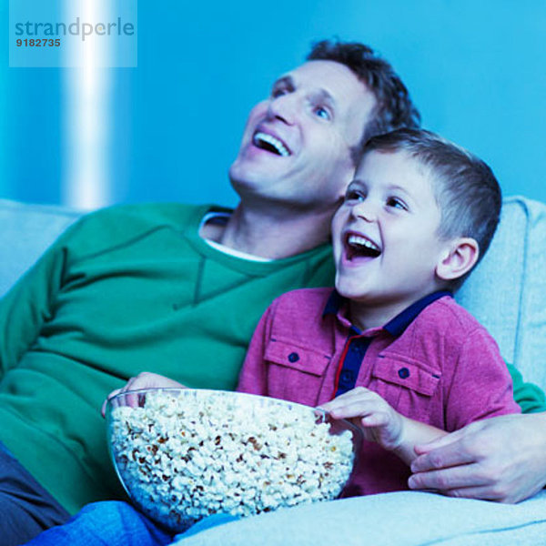 Vater und Sohn beim Fernsehen auf dem Sofa